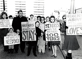 A group of parents and children dressed in coats hold up signs protesting the Christian Brothers withdrawal from St. Mary’s School in Yonkers.